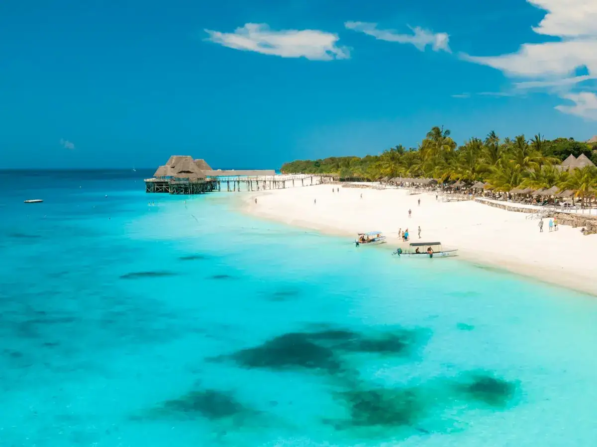 Praia de Zanzibar com água turquesa e um cais de madeira